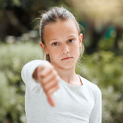 Buy stock photo Shot of an adorable little girl showing the thumbs down while  standing outside