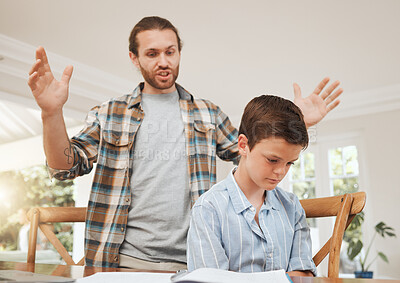 Buy stock photo Shot of a young father looking frustrated while helping his son with homework at home