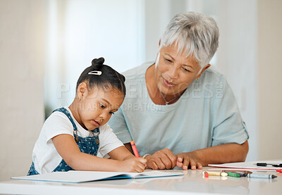 Buy stock photo Shot of a grandma helping her granddaughter at the kitchen table at home