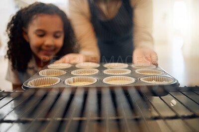 Buy stock photo Shot of a little girl watching her mother take a baking tray out of the oven
