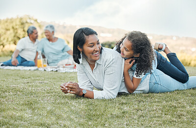 Buy stock photo Shot of a mother and daughter laying on the grass in a park