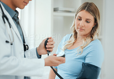 Buy stock photo Shot of a doctor using a blood pressure gauge during a checkup with his pregnant patient