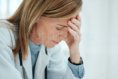 Buy stock photo Shot of a mature doctor sitting alone in her clinic and feeling stressed