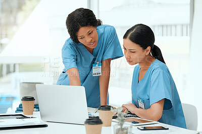 Buy stock photo Shot of two young female doctors using a laptop at a hospital