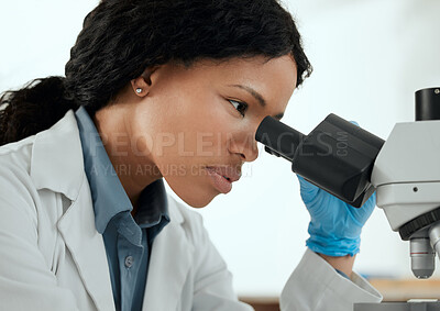 Buy stock photo Shot of a young woman using a microscope in a scientific lab