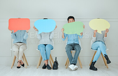 Buy stock photo Shot of a group of businesspeople holding up speech bubbles while waiting in line at an office