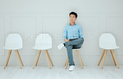 Buy stock photo Shot of a young man using a digital tablet while waiting in line at an office