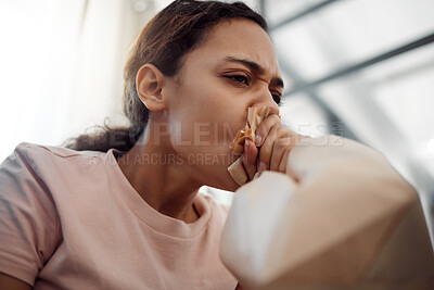 Buy stock photo Shot of a young woman experiencing a panic attack while sitting on the sofa at home
