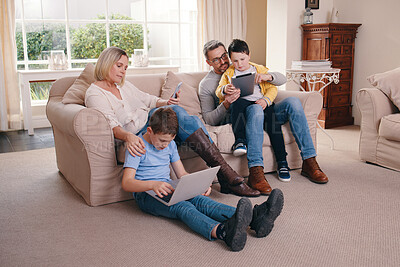 Buy stock photo Shot of a young family bonding while using their electronic devices together at home