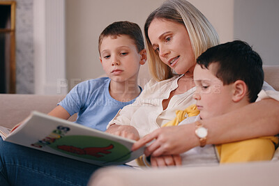 Buy stock photo Shot of a mother reading a book to her sons at home on the couch