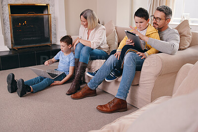Buy stock photo Shot of a young family bonding while using their electronic devices together at home