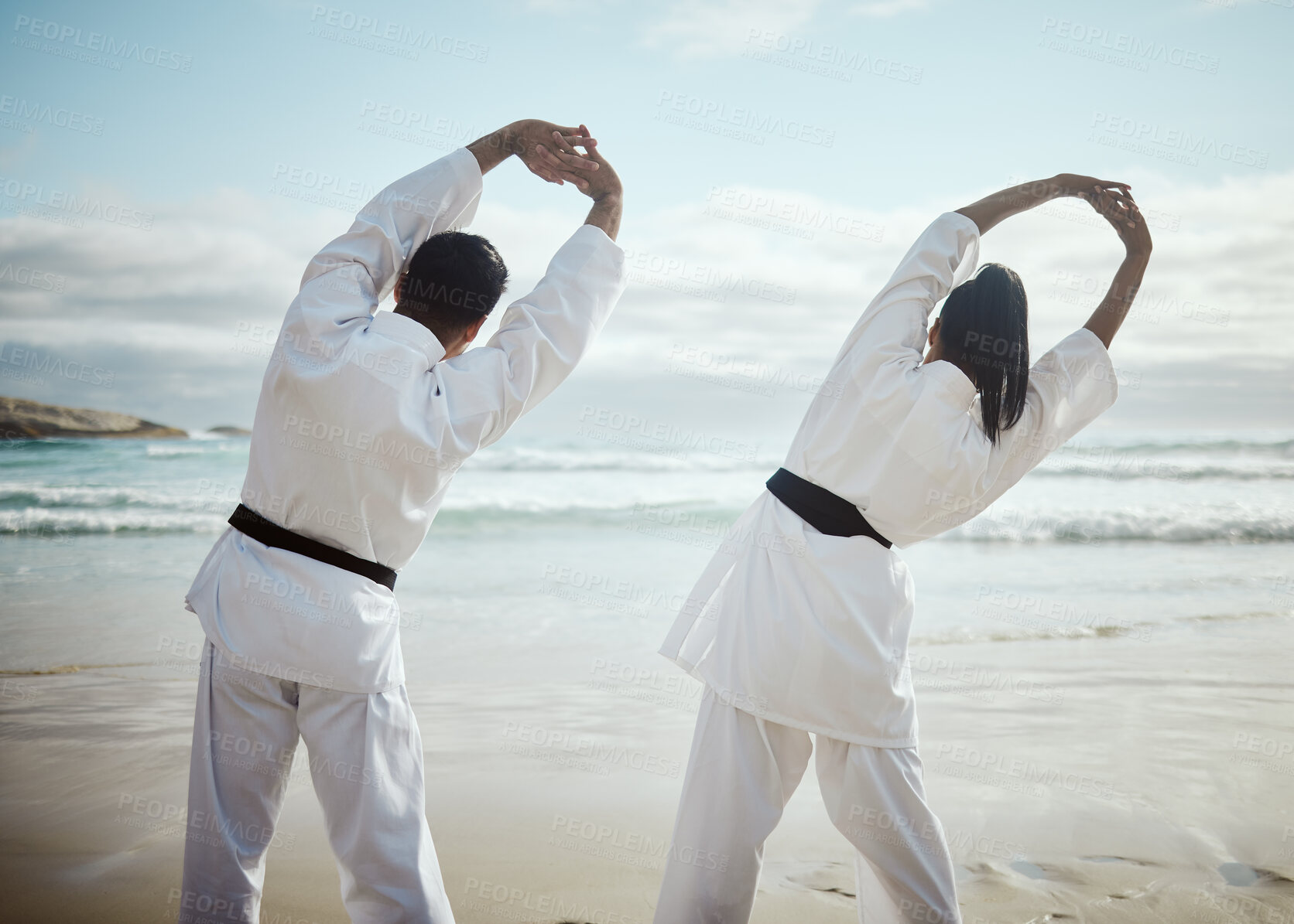 Buy stock photo Stretching, martial arts and people at beach for team training, flexible or back view. Ocean, karate and couple warm up for fight, fitness and warrior prepare healthy body for exercise lesson outdoor