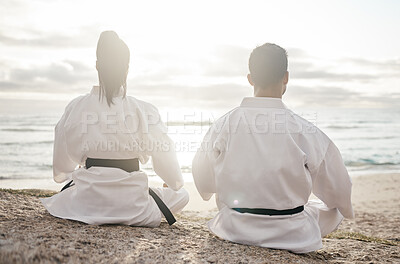Buy stock photo Rearview shot of two unrecognizable martial artists meditating while practicing karate on the beach