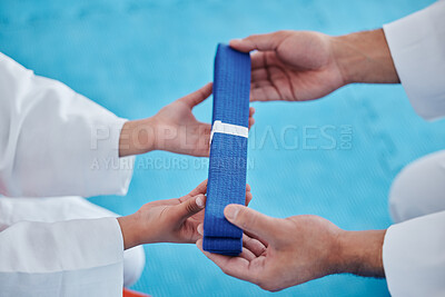 Buy stock photo Shot of an unrecognisable man handing his young student a blue karate belt in a studio