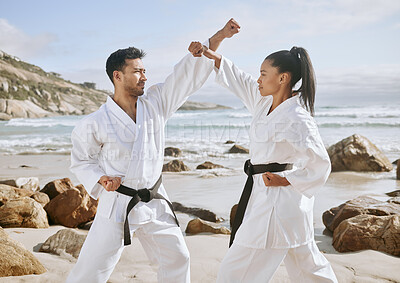 Buy stock photo Shot of two young martial artists practicing karate on the beach