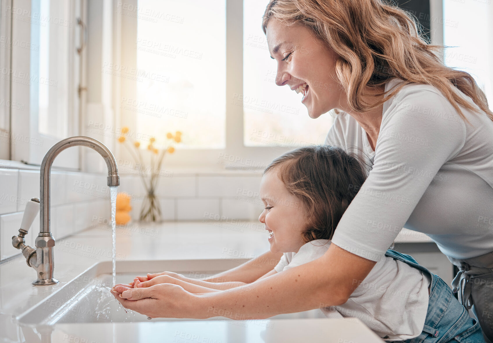 Buy stock photo Shot of a mother and daughter washing their hands in the kitchen