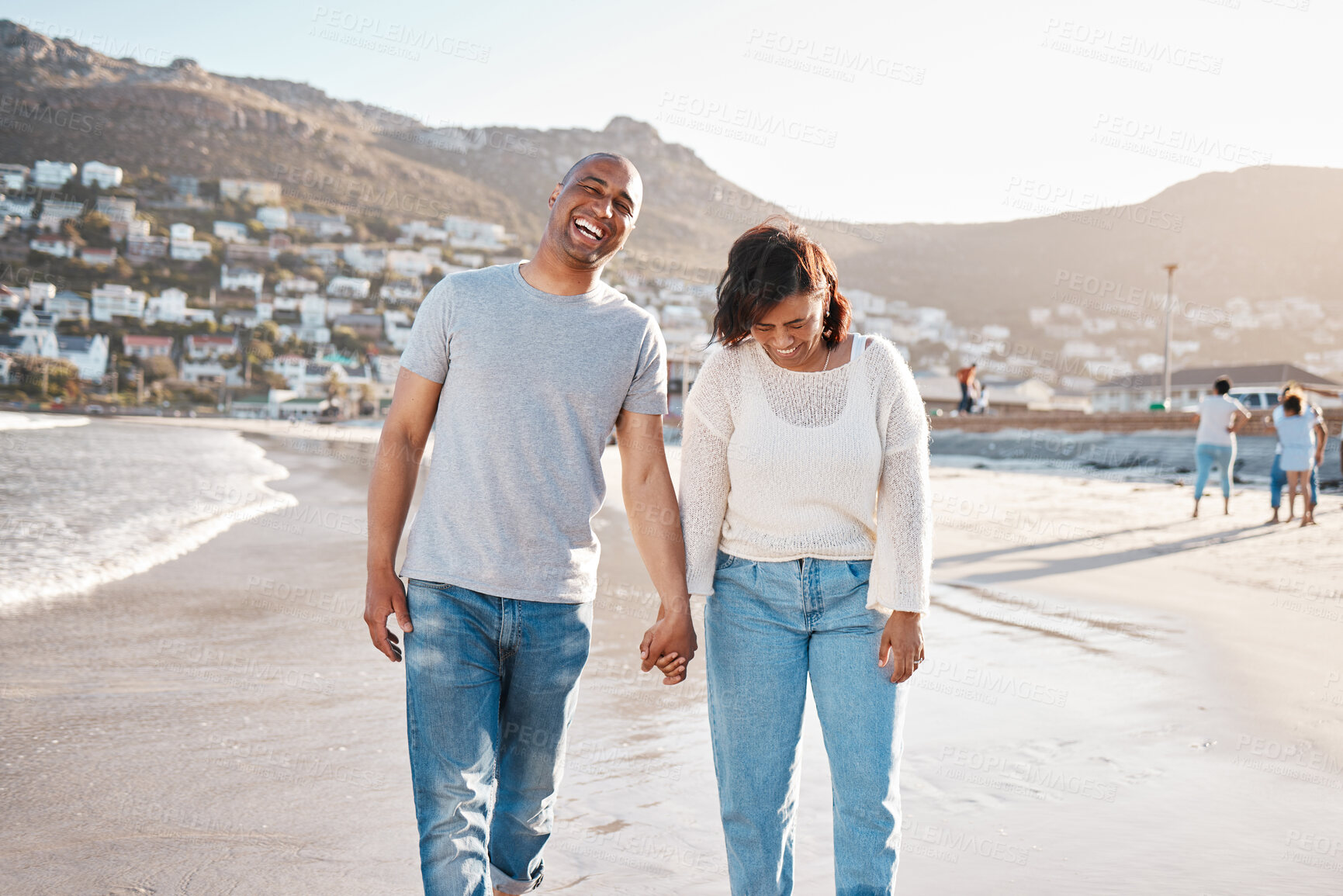 Buy stock photo Couple, laugh and holding hands at beach on vacation, romance and humor for bonding in marriage. People, happiness and outdoor holiday for relationship, funny conversation and support or love at sea