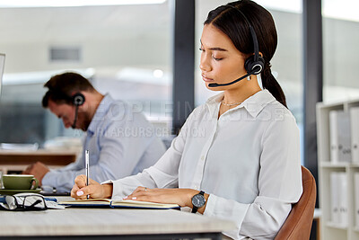 Buy stock photo Shot of a young businesswoman working in a call center making notes
