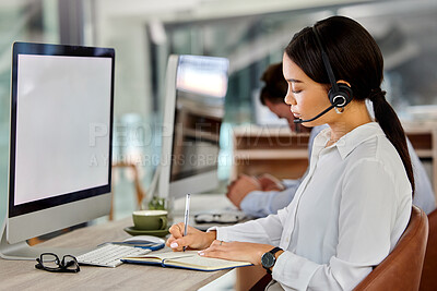 Buy stock photo Shot of a young businesswoman working in a call center making notes