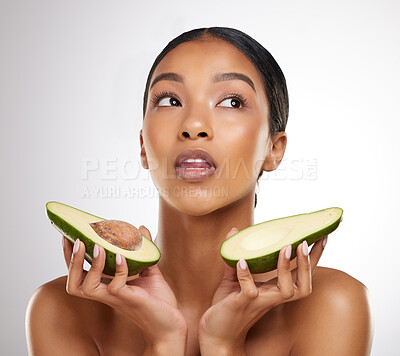 Buy stock photo Studio shot of an attractive young woman posing with two halves of an avocado against a grey background