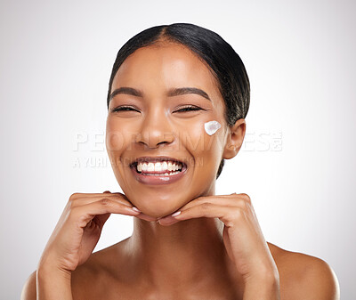 Buy stock photo Studio portrait of an attractive young woman applying face lotion against a grey background