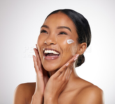 Buy stock photo Studio shot of an attractive young woman applying face lotion against a grey background