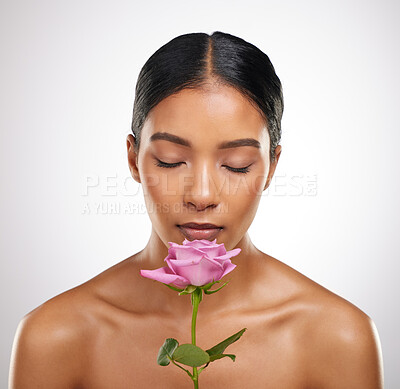 Buy stock photo Studio shot of an attractive young woman smelling a pink rose against a grey background