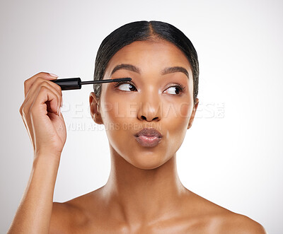 Buy stock photo Studio shot of an attractive young woman applying mascara against a grey background