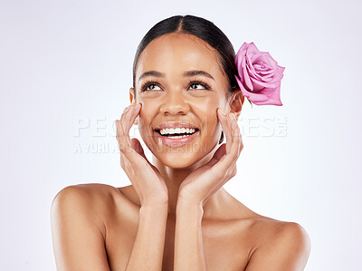 Buy stock photo Shot of a beautiful young woman posing with a rose tucked behind her ear against a studio background