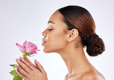 Buy stock photo Shot of a young woman posing holding a rose against a studio background