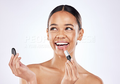 Buy stock photo Shot of a beautiful young woman applying lipstick against a studio background