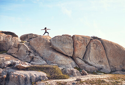 Buy stock photo Shot of a young woman practicing yoga on a boulder
