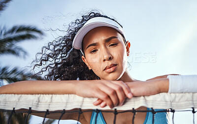 Buy stock photo Shot of an attractive young woman leaning on a tennis net and looking disappointed after practice
