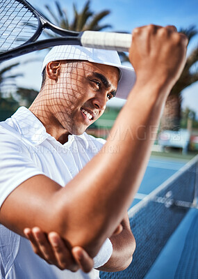 Buy stock photo Shot of a handsome young man standing alone and suffering from an elbow injury during a game of tennis