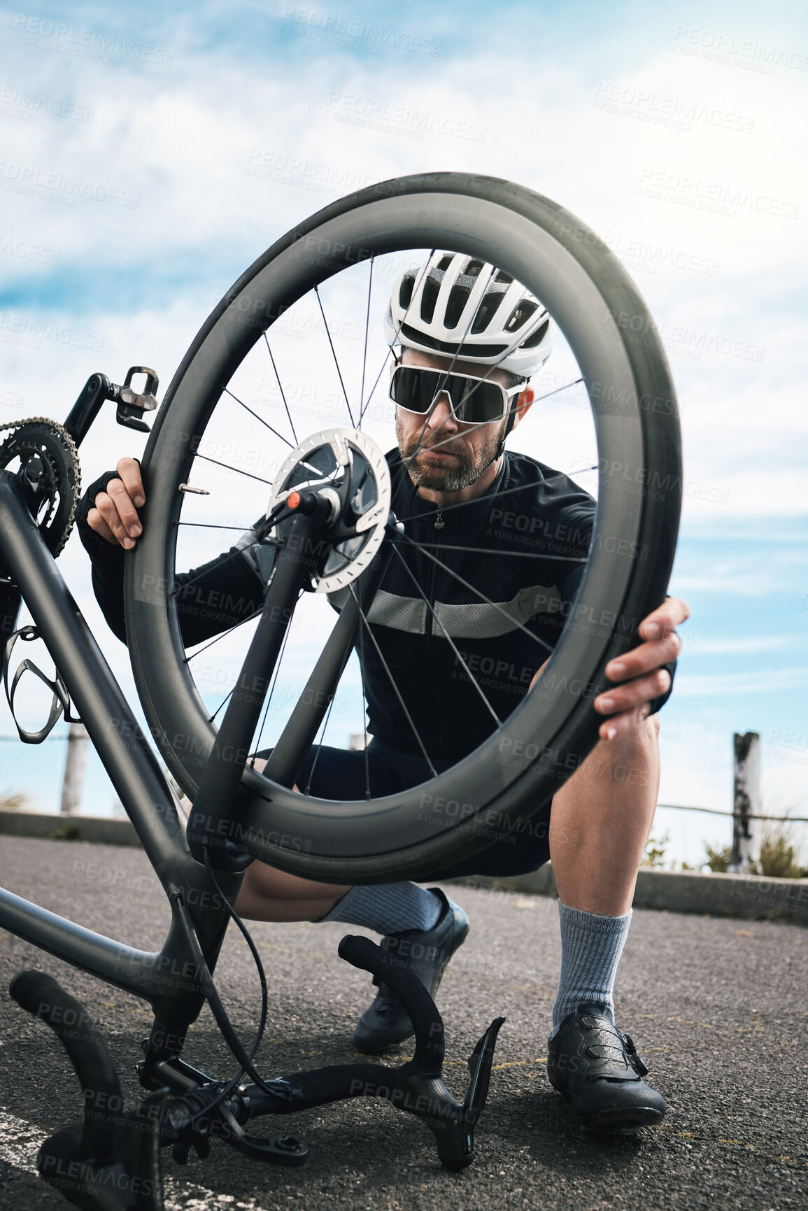 Buy stock photo Full length shot of a handsome mature man checking his tyre while cycling outdoors