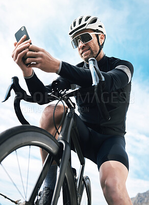 Buy stock photo Cropped shot of a handsome mature man sending a text while cycling outdoors