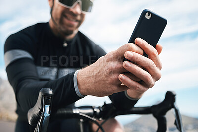 Buy stock photo Cropped shot of a handsome mature man sending a text while cycling outdoors