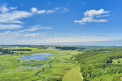 Buy stock photo Beautiful, green and open countryside landscape with a lake, grass, and trees surrounding farm houses. Aerial view of farming land or eco clean flatland with clouds blue sky background and copy space