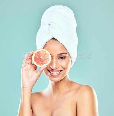 Buy stock photo Shot of a young woman covering her face with a grapefruit against a studio background
