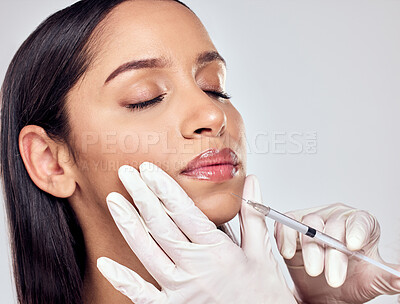 Buy stock photo Shot of a woman having her lips injected with filler against a studio background