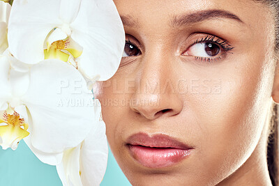 Buy stock photo Shot of a beautiful young woman covering her face with an orchid against a studio background