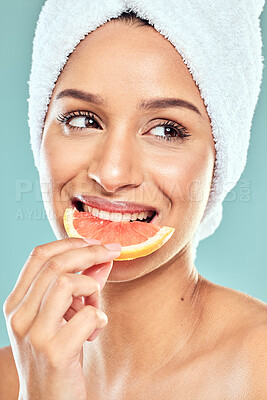 Buy stock photo Shot of a woman biting into a slice of grapefruit against a studio background
