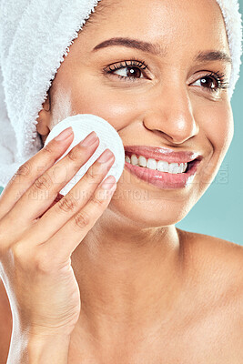 Buy stock photo Shot of a young woman applying product to her face using a cotton pad against a studio background
