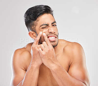 Buy stock photo Shot of a young man popping a pimple against a grey background