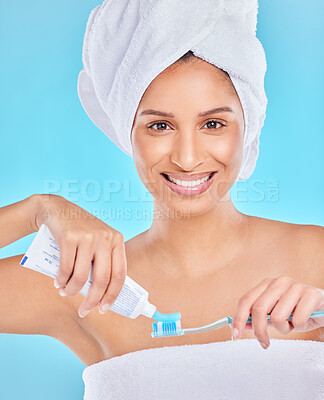 Buy stock photo Studio portrait of an attractive young woman brushing her teeth against a blue background