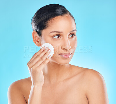 Buy stock photo Studio shot of an attractive young woman exfoliating her face against a blue background