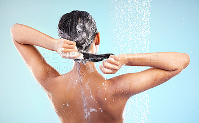 Buy stock photo Shot of an unrecognizable woman washing her hair against a blue background