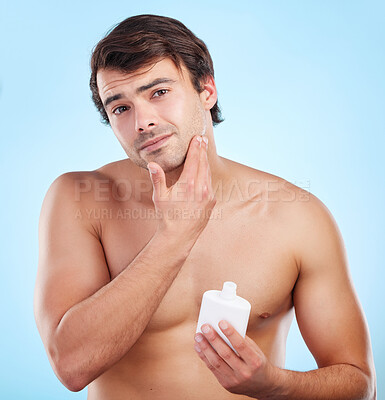 Buy stock photo Skincare, man and moisturizer in portrait for wellness, after shave or lotion in studio. Male person, grooming and face product on blue background with container, skin cream or dermatology or routine