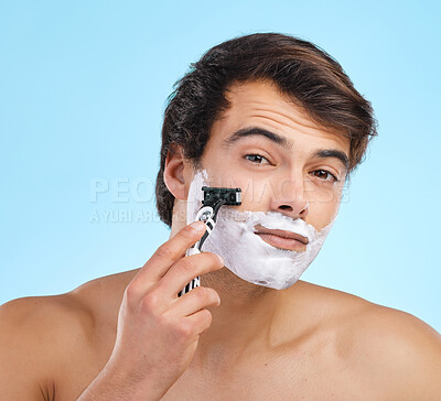 Buy stock photo Portrait, razor and man shaving in studio for hair removal, hygiene or grooming for health isolated on blue background. Cream, face and model cut beard for skincare, beauty and cleaning for wellness