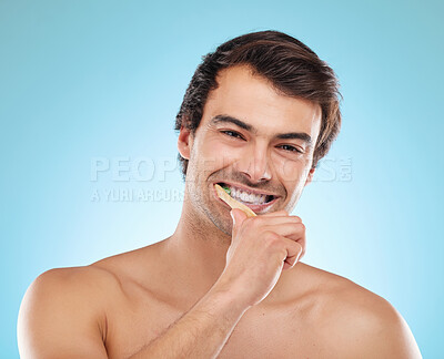 Buy stock photo Portrait, brushing teeth and man with dental hygiene, wellness and grooming routine on blue studio background. Face, person or model with oral health, cleaning mouth or remove plaque for fresh breath